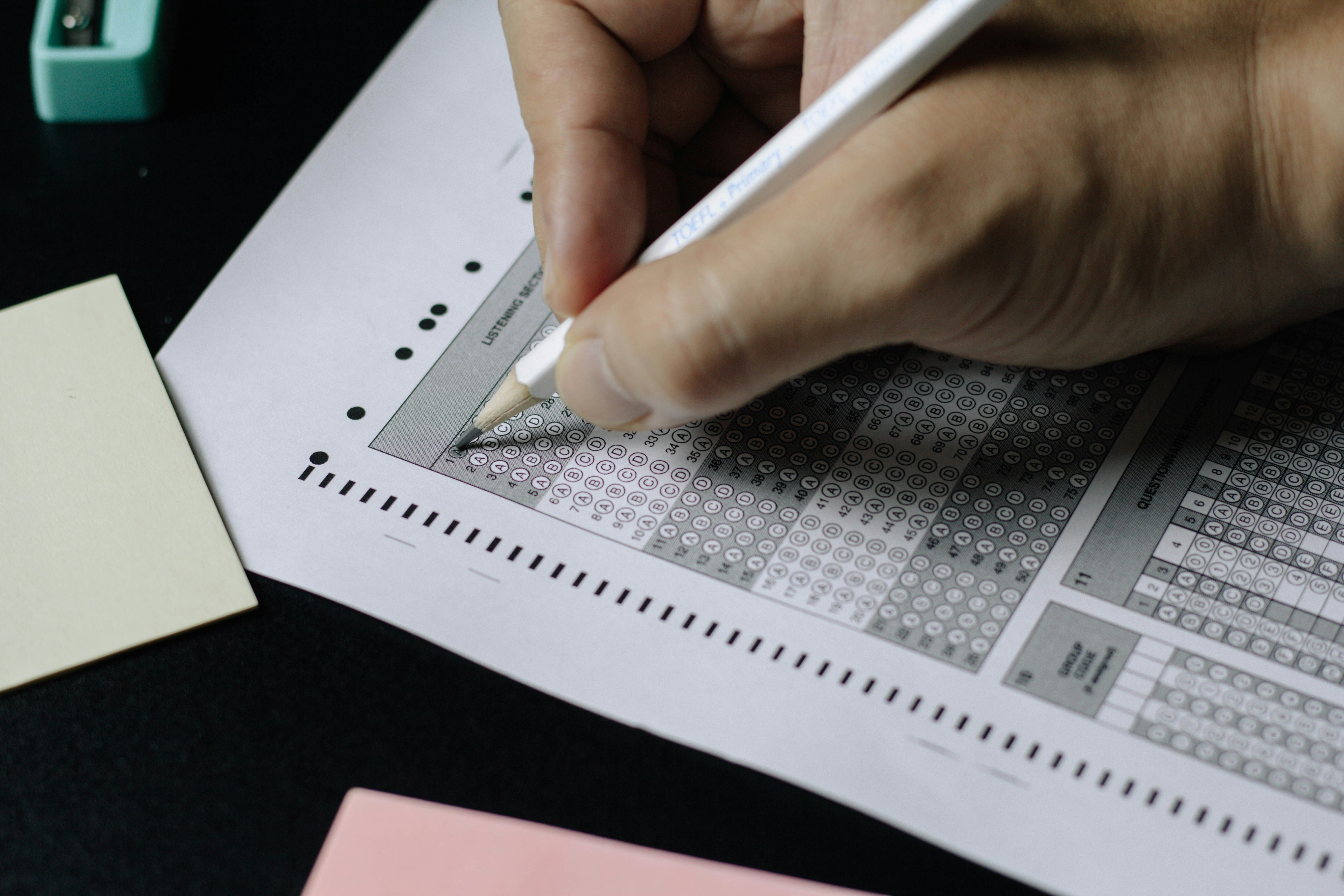 Hand filling a competitive exam OMR answer sheet with a pencil — banking exam preparation