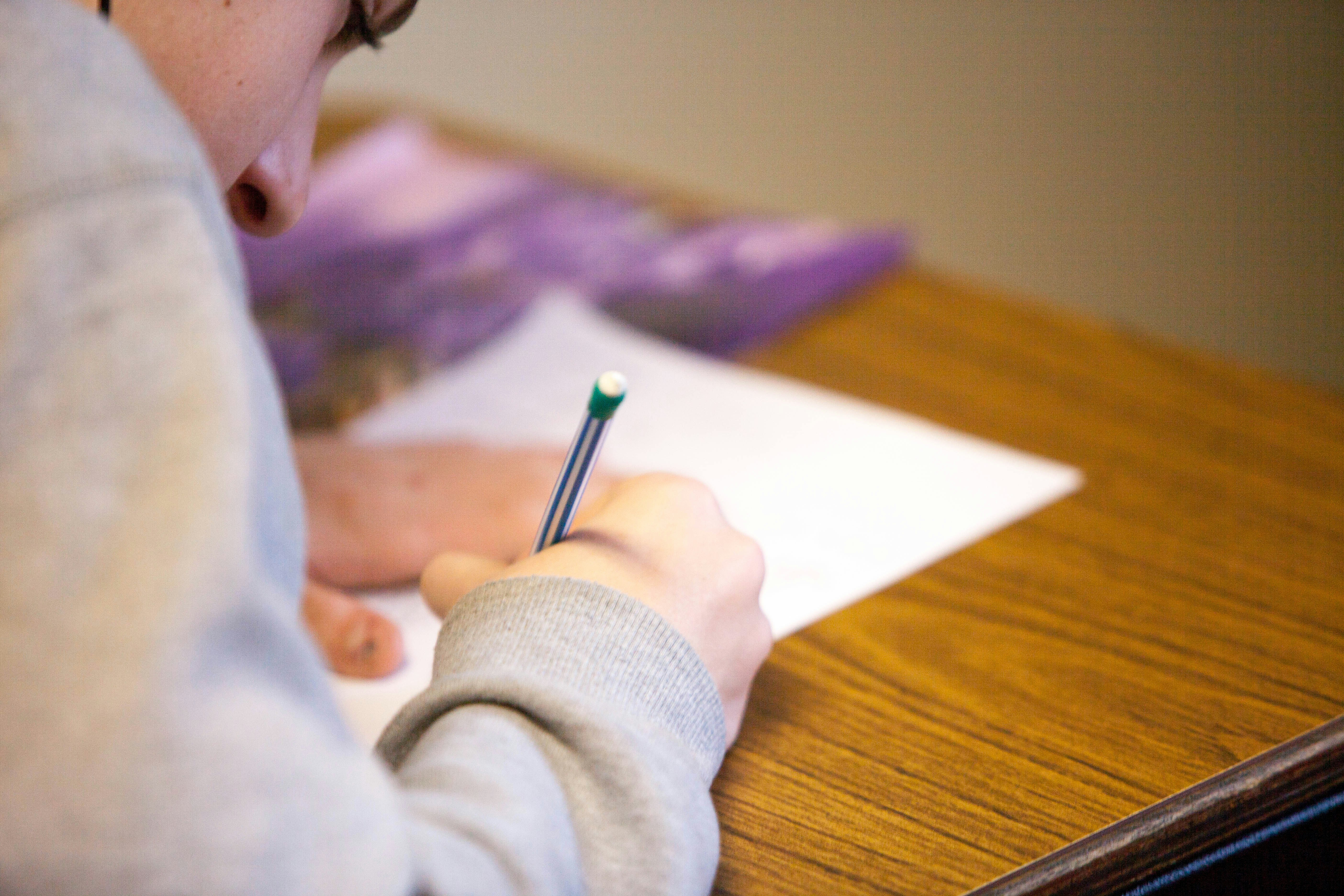 Student writing with a pencil on paper — Railway NTPC exam preparation